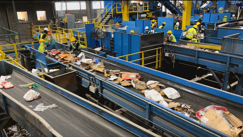 MES and contractors sort recyclable goods as they move across blue conveyor belts at the Prince George's County Materials Recovery Facility.