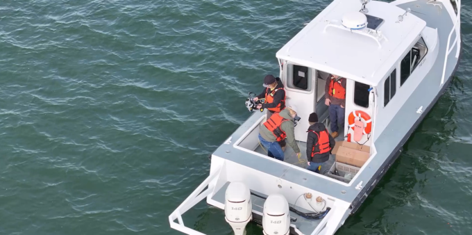 Aerial image of a small boat in the Chesapeake Bay with three MES staff members on board.